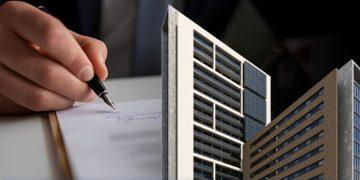 Close-up of a hand signing a document with a miniature modern skyscraper model in the foreground, implying real estate or architecture contracts.