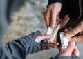 Close-up of hands exchanging cash for a small transparent bag of white pills.